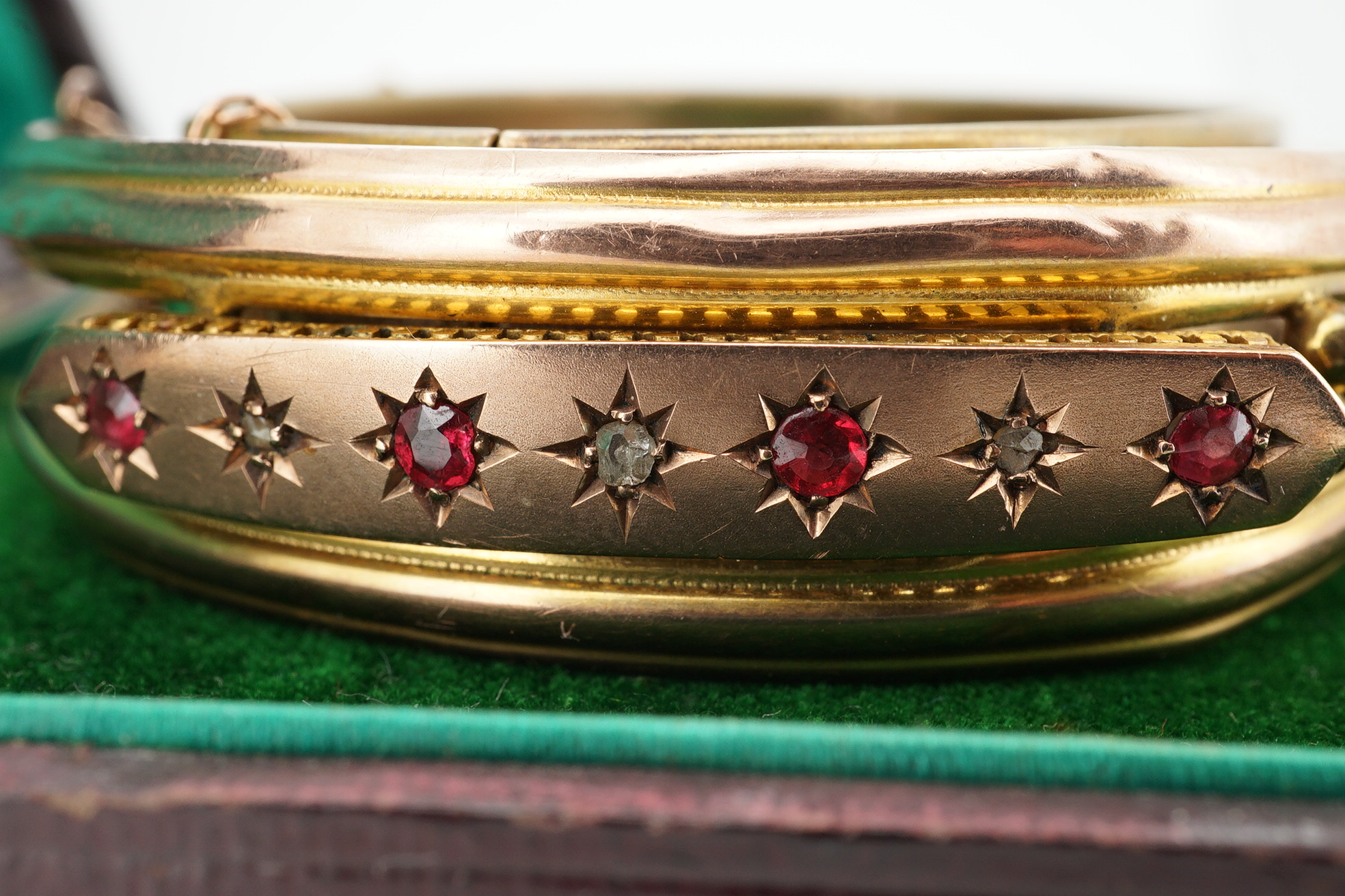 An Edwardian 9ct gold, and gypsy set ruby and diamond set hinged bangle, gross 11.4 grams, together with a gilt metal hinged bangle. Condition - poor.